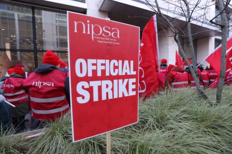 NIPSA union sign reading official strike with NIPSA members pictured in background not facing camera