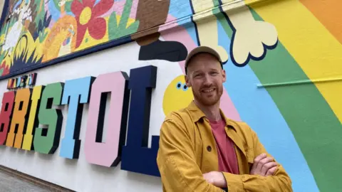 BBC Dave Bain in front of the mural