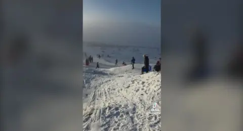 People enjoying the snow on Black Mountain, Swansea, a still from a video taken of people using sledges