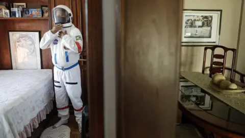 AFP Tercio Galdino, 66, wears his protective "space suit" inside his house