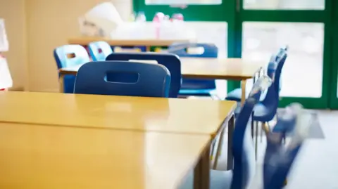 A general view picture of plastic chairs and desks in a classroom.