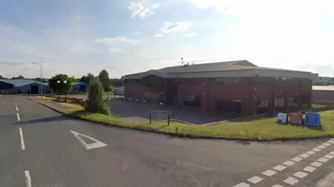 Google Road sign of Little Money Road with commercial office buildings and warehouses in the background