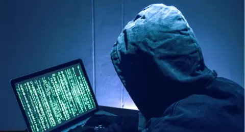 Getty Images hooded man looking at a computer screen