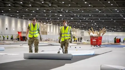 MOD A hand-out picture provided by the British Ministry of Defence showing soldiers from 1 Royal Anglian Regiment as they assist with building the Nightingale Hospital at the ExCel conference centre in London