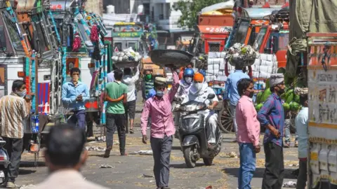 Getty Images People carrying bundles of vegetables during lockdown, in Azadpur Mandi on May 7, 2020 in New Delhi, India