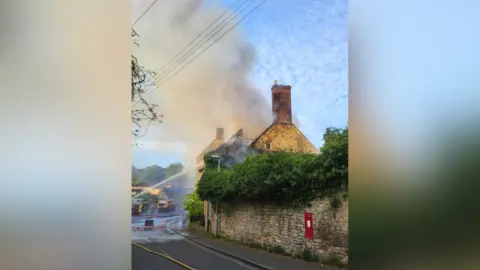 DWFRS Water being sprayed on a building which has smoke coming out of it 