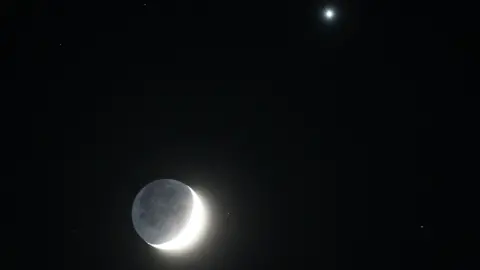 PA Media In the UK's Whitley Bay, a shining waxing crescent moon glows with Venus to the right