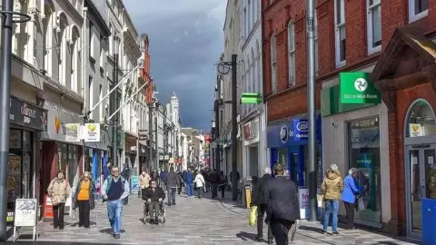 MANX SCENES Strand Street, a pedestrianised shopping street with a lot of people walking on a clear day.