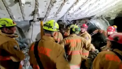 MIAMI DADE FIRE DEPARTMENT/Reuters Fire crew members work at the basement parking garage of a partially collapsed residential building in Surfside, Miami-Dade County, Florida, U.S., June 24, 2021.