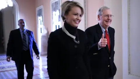 Getty Images Senate Majority Leader Mitch McConnell (R-KY) gives a thumbs-up as he and his Director of Operations Stephanie Muchow head for the Senate floor at the U.S. Capitol December 1, 2017 in Washington, DC