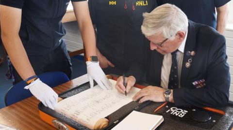 Hartlepool RNLI chairman Malcolm Cook adding his signature to the scroll