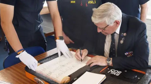 RNLI/Tom Collins Hartlepool RNLI chairman Malcolm Cook adding his signature to the scroll