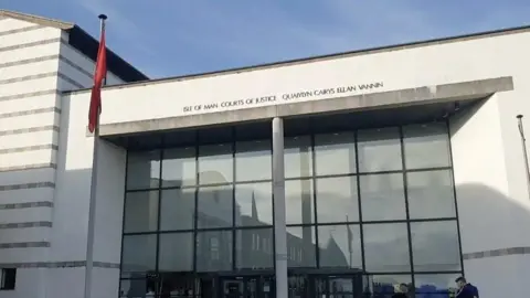 BBC The outside of Douglas Courthouse, which is a white and glass-fronted building and has Isle of Man Courts of Justice in English and Manx above the entrance.