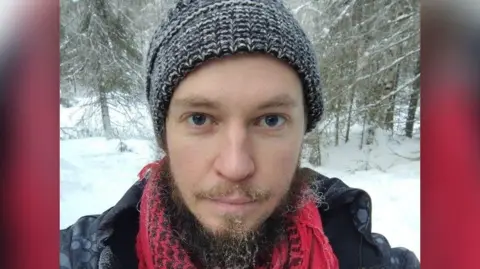 Steve Gay wearing a woolly black hat and a red scarf.