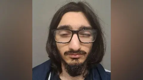 Eastern Region Special Operations Unit A custody image shows a man with long hair and glasses