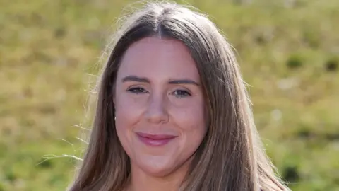 Nikki Penrice now, three years after she was diagnosed with bowel cancer at eight months pregnant. She has long, straight, brown hair and smiles at the camera.