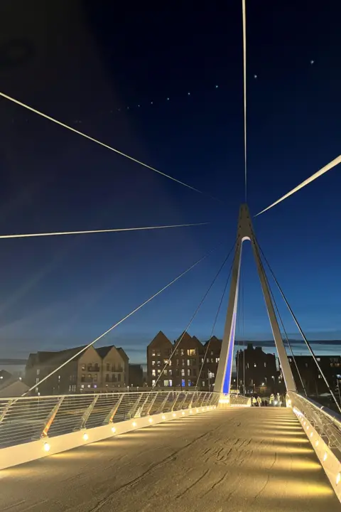 Jon Rowe Six cables pointing in different directions catching a white light against a dark sky.