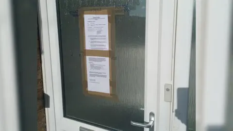 North Yorkshire Police A front door with two sheets of paper taped to it, alongside blue lettering saying "police evidence".