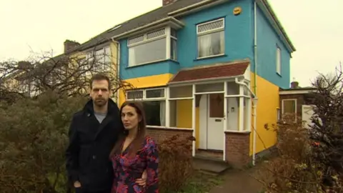 Couple next to house they have painted blue and white