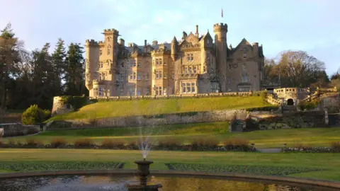 Getty Images Skibo Castle, an imposing building being hit by sunlight with rolling lawns in front and a fountain