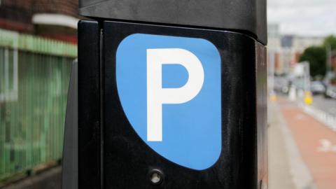 A blue sign reading 'P' on the side of a black parking meter