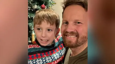 James Hunt James and Tommy in Christmas jumpers with a tree behind