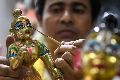 Narinder Nanu / AFP An artist adds the finishing touches to an idol of Hindu deity Lord Krishna