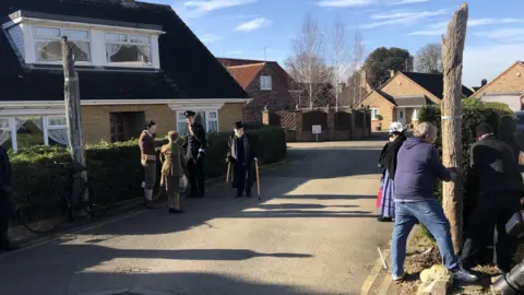 John Devine/BBC A group of people watching a whalebone being put back in place