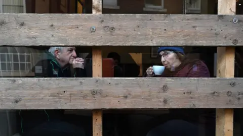 AFP/Getty images A couple sit inside a boarded-up coffee shop ahead of the annual Royal Shrovetide football match