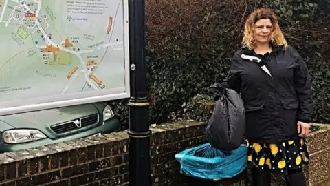 BBC Olivia Post holds a bag over a council bin