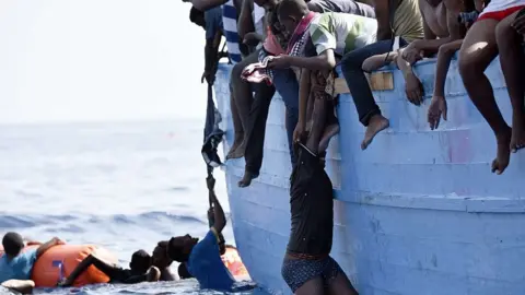 AFP A migrant hangs from a boat as they wait to be rescued as they drift in the Mediterranean Sea, some 12 nautical miles north of Libya, on October 4, 2016.