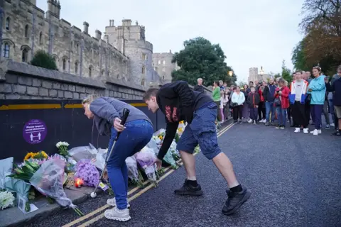 Jonathan Brady/PA Mourners gather laying flowers outside Windsor Castle