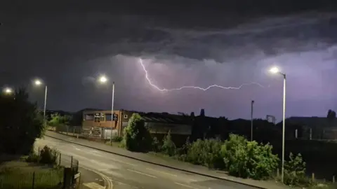 Buckeroo93 A lightning strike in the sky above a residential area of Wolverhampton. It is night and the street lights are on.