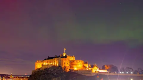 Roy Munro The purple and green sky above Edinburgh, the castle is lit up below.