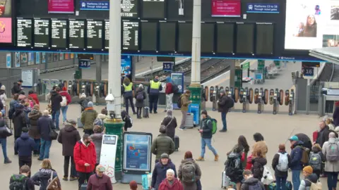 PA Media Rail passengers walking around Edinburgh Waverley.