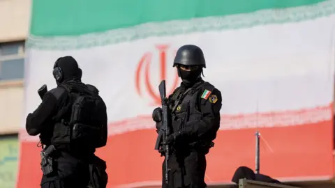 Armed Iranian security personnel watch over a pro-government rally in Tehran, Iran (12 January 2026)
