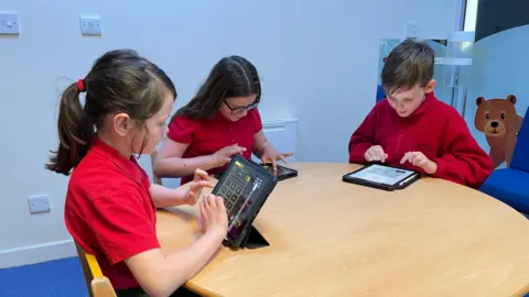 Three pupils are using iPads to play a game that teaches times-tables