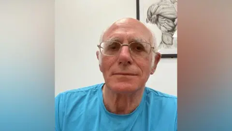 Supplied A selfie-style image of an elderly man wearing a blue T-shirt and glasses. He is looking into the camera. 