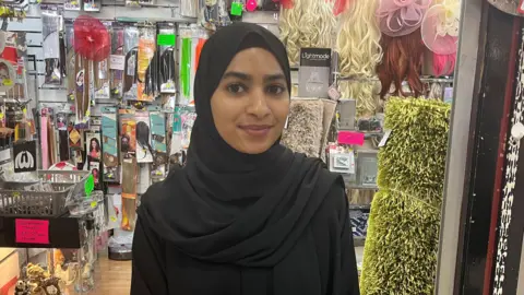 A young woman wearing a hijab in front of a store