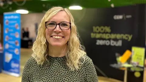 Gemma Boss from Chalk and Ward with black glasses and an olive and black patterned top
