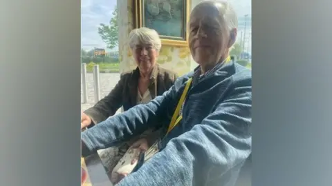 Inspire Youth Zone Bill and his wife Vivien are sitting down side by side. They are both smiling. 