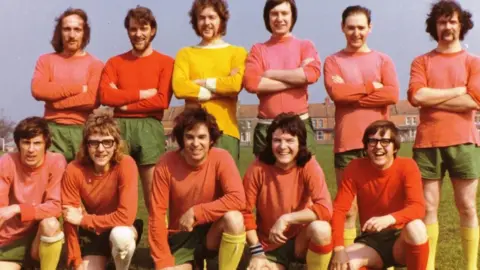 Terry Maine A dated looking picture of a group of men wearing red tops, green shorts and yellow socks for a football match all looking at the camera