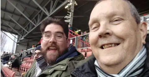 Two men sitting in the terraces wearing warm clothes