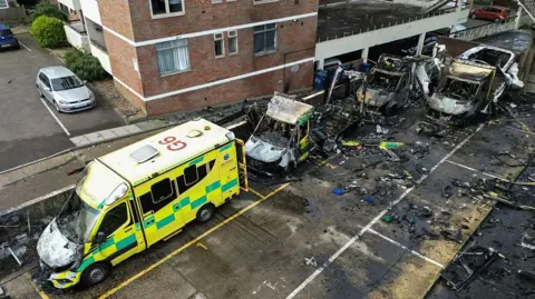 Getty Images Three completely burnt out ambulances and a fourth partly damaged ambulance in a car park