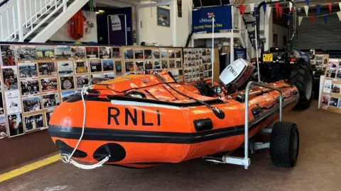 A small orange lifeboat in a lifeboat station