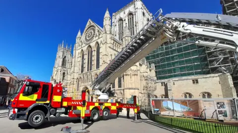 North Yorkshire Fire & Rescue Service A fire engine with an aerial platform is stationed outside York Minster on a sunny day.
