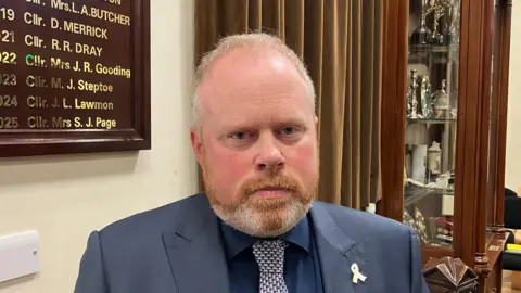 Matt Knight/BBC A head and shoulders picture of Councillor James Newport in the Rochford District Council council chamber