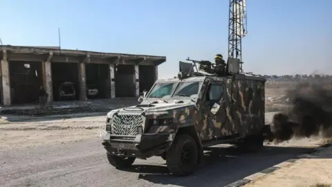 Anadolu Rebel fighters led by Hayat Tahrir al-Sham (HTS) drive an armoured vehicle during an offensive against government forces in north-western Syria (28 November 2024)