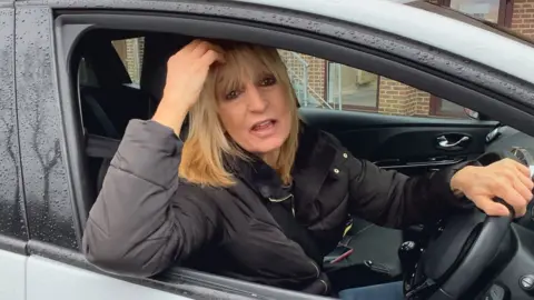 Blonde woman sat in car in driver's seat