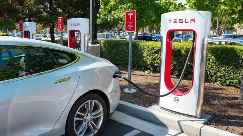 Tesla automobile plugged in and charging at a Supercharger rapid battery charging station 